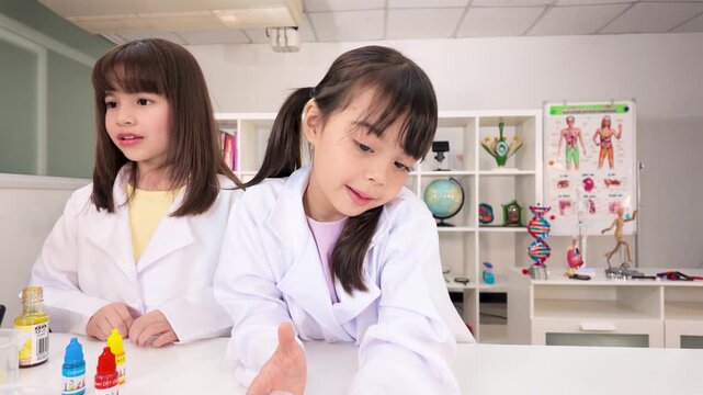 Two Elementary Girls in Lab Coats Conducting Science Experiments in Classroom