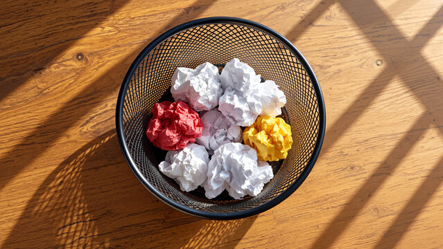 Top View of Colorful and White Crumpled Paper Balls in Black Mesh Trash Can on Wooden Table, Creative Block and Idea Concept