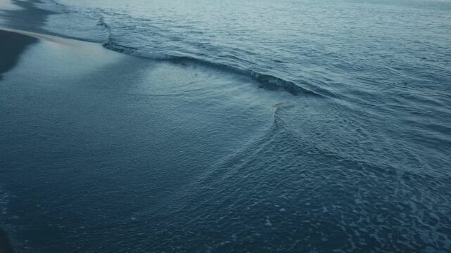 Gentle Waves Lapping Quietly on a Dark Blue Beach