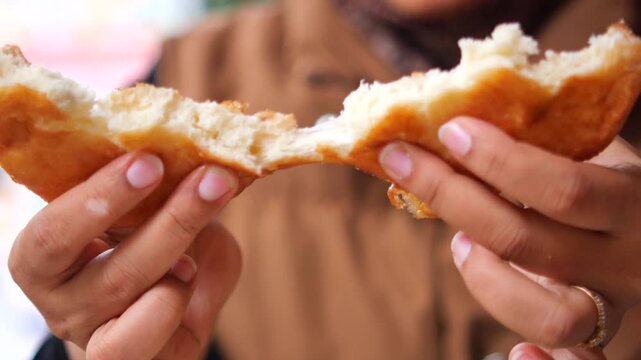 Close up video of person hands tearing apart freshly baked bread for breakfast.