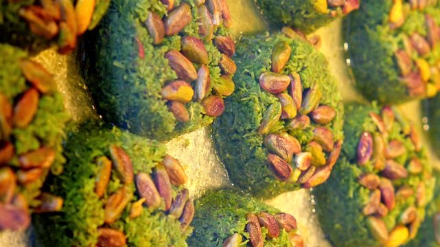 Delicious turkish pistachio desserts soaking in sweet syrup closeup dynamic food footage.