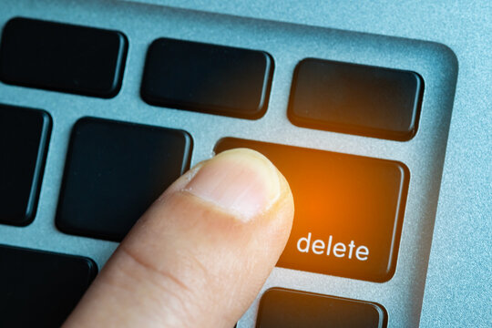 Finger of the computer user, he presses the delete button on the computer keyboard.