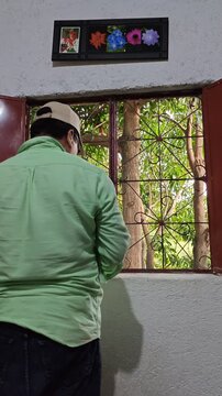Young Man Applying Paint With Brush On Window Frame