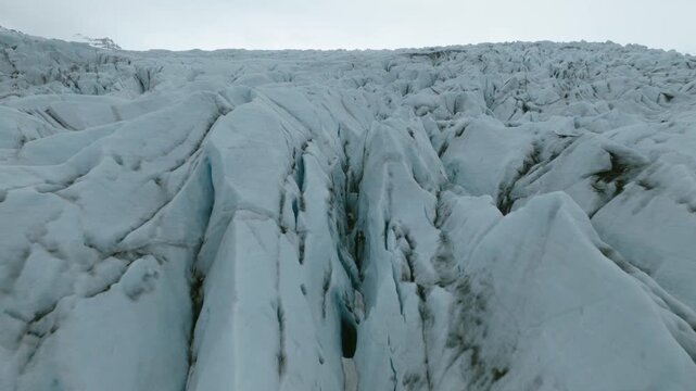 Heinabergsjokull ice displays deep channels, fractures, sediment bands and sculpted glacial textures in Vatnajokull National Park, Southeast Iceland, drone forward flyover.