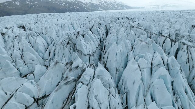 Deep crevasses and sharply fractured blue ice dominate the surface of Fjallsjokull in Orafi, South Iceland, revealing complex glacial deformation and layered ice textures, parallax pullback