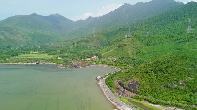 Emerald green mountains tower over a calm bay where a quiet road