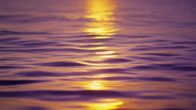 Golden sun reflection ripples on purple water surface during twilight