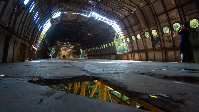 Wide perspective inside abandoned aircraft fuselage with exposed metal floor frame, urban exploration