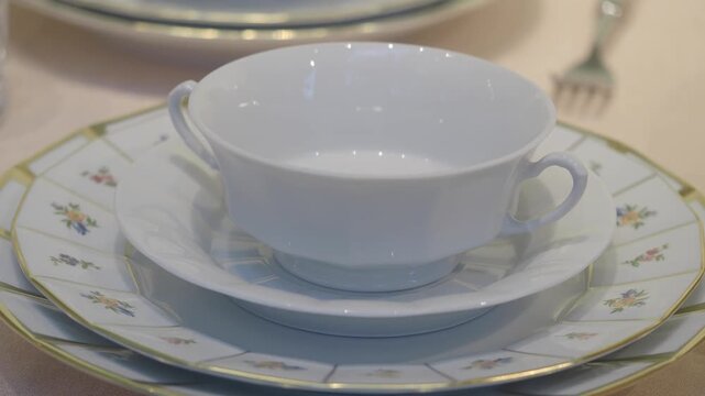 Elegant white porcelain teacup and saucer set with floral design and gold trim on table.