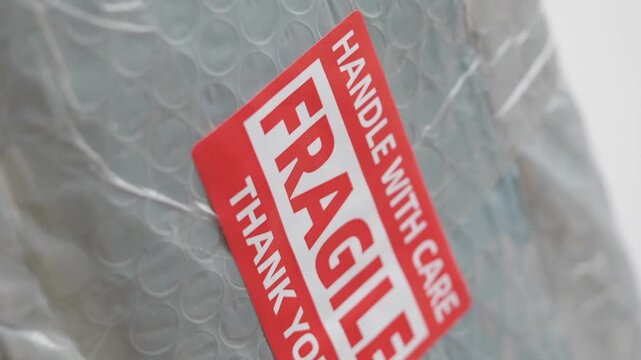 Close up motion of a fragile thank you label on bubble wrap packaging with care.