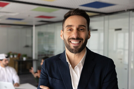 Headshot portrait of smiling Hispanic businessman, successful male corporate team member standing in office meeting room, represents leadership, career growth, confidence, professionalism in business