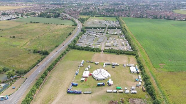Aerial view shows festival grounds with large tents and parked vehicles