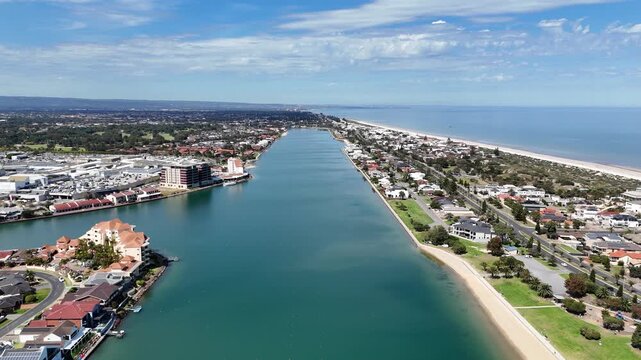Aerial drone view overlooking West Lakes, Adelaide, South Australia, capturing the long lake channel flanked by upscale waterfront residential estates, nearby shopping complexes, sandy beaches
