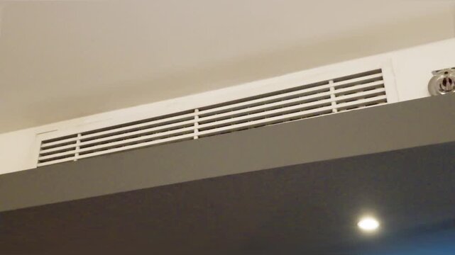 Modern linear air conditioning vent grille installed in a white ceiling bulkhead.