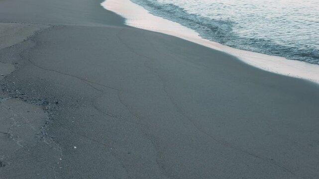 Gentle Waves Breaking on a Wide Blue-Gray Sandy Beach