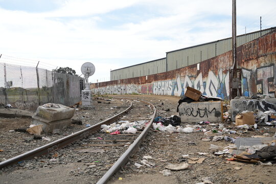 Oakland, California - Oct. 2, 2026: Railroad tracks lined with trash and graffiti-lined walls.