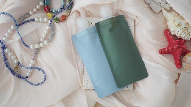 Minimalist skincare pouch products on draped fabric with sea shells and beaded necklaces.