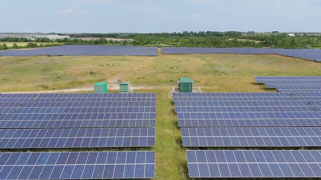 Solar panels stretch across green fields under clear skies