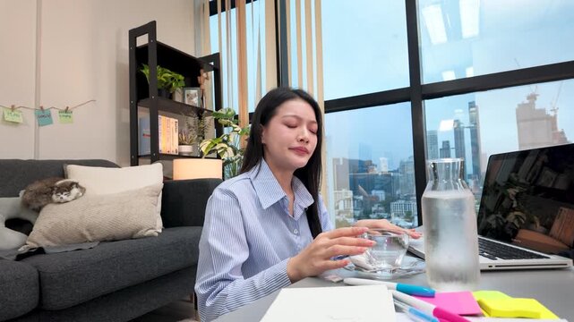 Tired Asian Freelance Woman Yawning at Laptop Desk in City Apartment