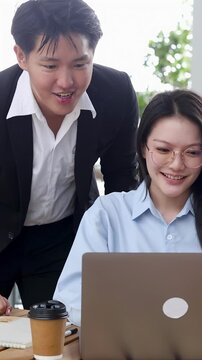Asian Business Colleagues Looking at Laptop Screen Together in Modern Office