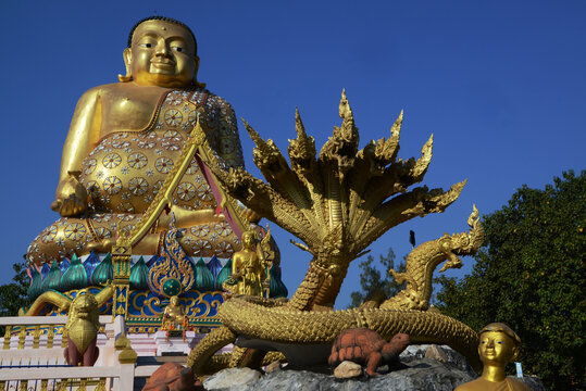 A large brilliantly gold-colored statue of Phra Maha Kaccayana Thera, holding a holy water vessel representing the 76 provinces standing 20 meters at Wat Lang San Prasit.