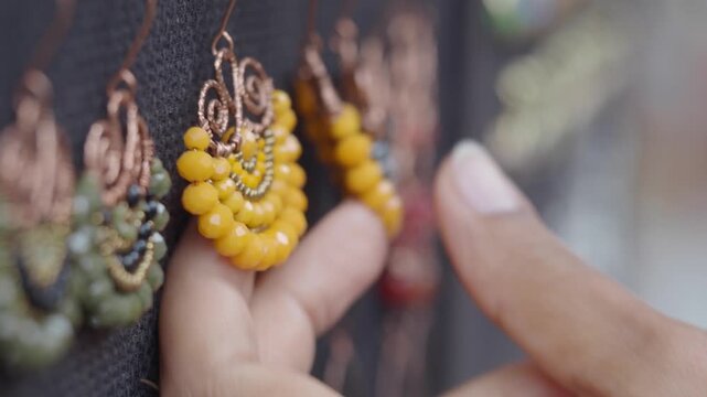 Hand selects unique beaded earrings displaying vibrant colors and intricate metalwork.