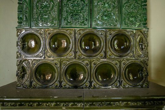 Abandoned historic villa interior with ornate tile stove, wooden staircase and attic