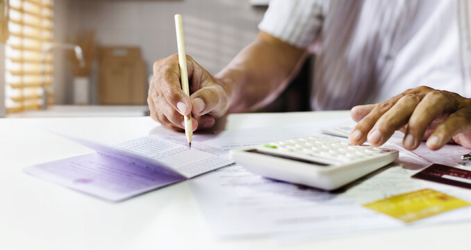 close-up shot, asian man checking balance in passbook and calculate financial bills, receipt from credit card debt before paying