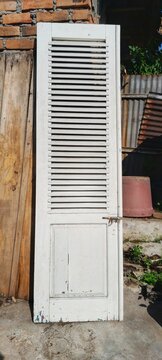 White wooden louvered door shutter on rustic wooden wall background