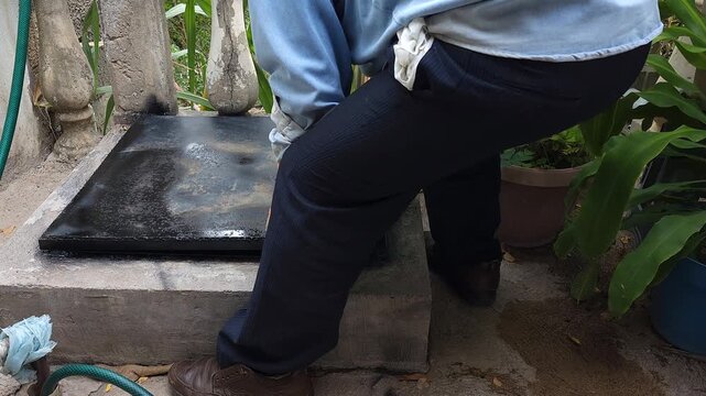 Young Man Positioning Metal Cistern Cover Before Painting