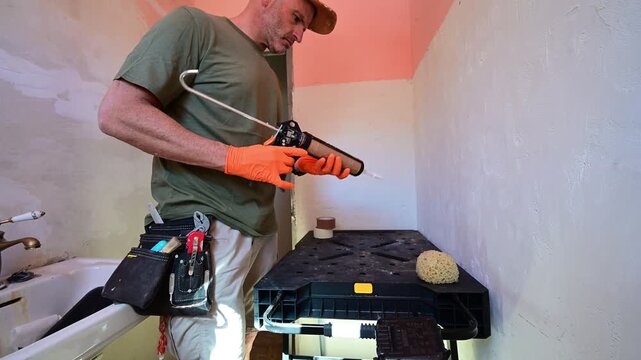 Plumber applying silicone sealant in a bathroom renovation