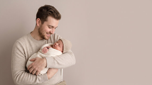 A young father holding his newborn baby wrapped in a white blanket and wearing a small hat, ad social media download thambnail poster web template event festival 2026 2027 2028
