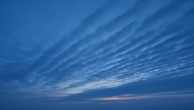 Cold blue twilight sky with fast moving stratocumulus clouds forming dynamic diagonal lines