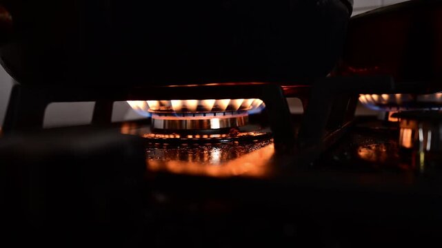Gas stove burner with blue flames cooking in the dark