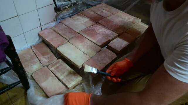 Artisan cleaning and waxing terracotta bricks for floor restoration
