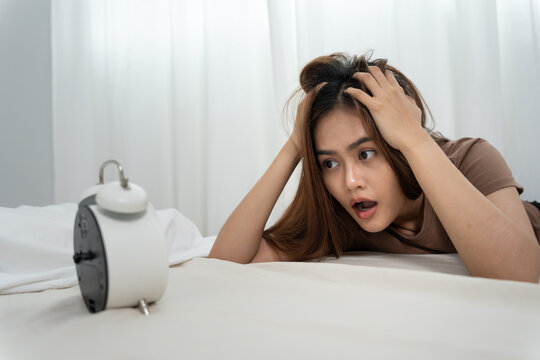 Shocked Asia young woman looking at clock alarm, lady is late appointment or work or class study, overslept, difficulty get up in mornings, time worried, not on time, sleepy, over due, Hurry up time