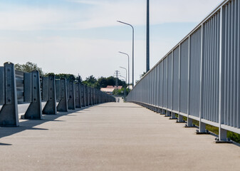ścieżka idąca wzdłuż drogi osłonięta barierkami i kratką w porze letniej, błękitne niebo, z prawie bezchmurną pogodą © mbugajsky