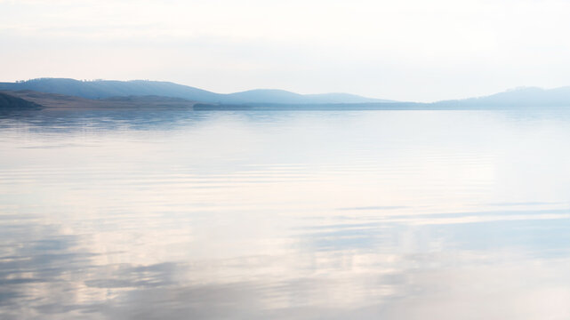 Mountain lake at foggy morning. Clouds reflected in the calm water
