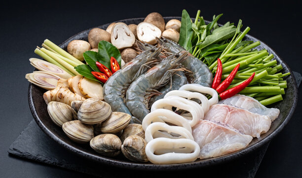 Lau Thai / Lau Hai San (Vietnamese Seafood Hot Pot): An unbaked, artfully arranged platter of fresh seafood for hot pot featuring raw tiger prawns, calamari rings, fish fillets, and clams,