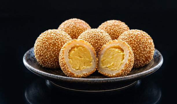 Banh Cam / Banh Xai (Vietnamese Sesame Balls): Golden-brown fried glutinous rice balls coated in toasted white sesame seeds, filled with sweet mung bean paste,