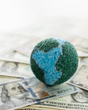 global finances and world economics concept. globe and dollar banknote money show debt in financial market. vertical view.