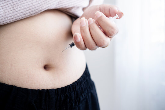 Close up of woman injecting insulin syringe into abdomen belly fat at home, subcutaneous injection, hormone therapy, diabetes treatment, weight loss, medication healthcare medicine concept