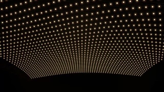Abstract glowing dots form a dynamic wave pattern in a dark studio with subtle camera movement
