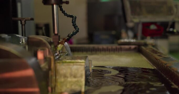 Milling machine cutting a large steel mould with cutting fluid flowing in a machining shop