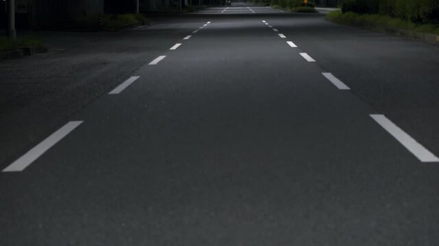 街灯の光が照らす夜の三車線道路、静かな雰囲気が広がる車道と奥行きのある風景