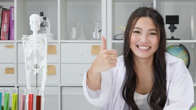 Smiling Teenage Girl in Lab Coat Giving Thumbs Up in Science Classroom