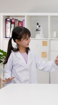 Little Girl Wearing Lab Coat Dancing Playfully in Classroom