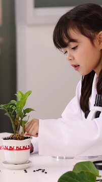 Young Girl in Lab Coat Studying Seeds and Potted Plant in Classroom