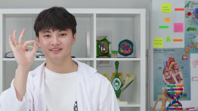 Smiling Teenage Student in Lab Coat Giving OK Hand Gesture