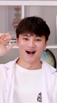 Teenage Boy in Lab Coat Smiling and Waving in Science Classroom